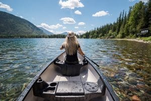 shot from inside a canoe of woman rowing on beautiful clear river water - sobriety