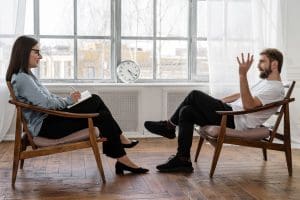 man speaking to woman therapist in bright well lit room