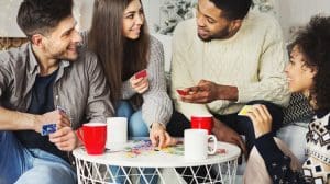 New Year's Eve Sober, group of young adult friends playing card games in front of Christmas tree - New Year's Eve sober