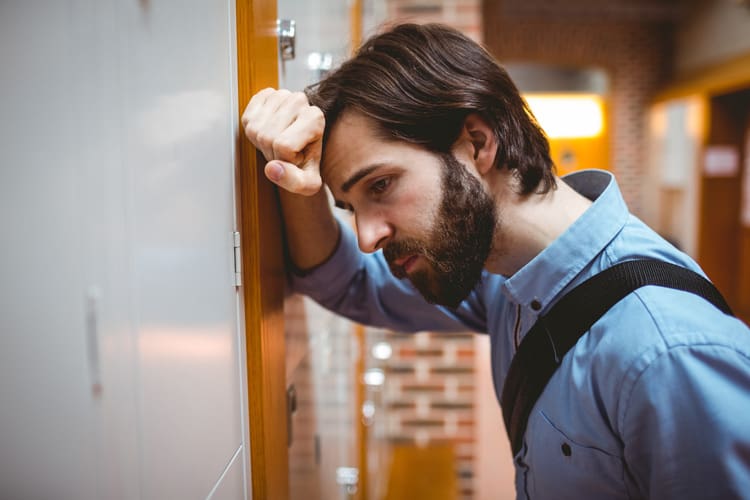 Post-Acute Withdrawal Syndrome, young bearded college student looking stressed and leaning against a locker - post-acute withdrawal syndrome