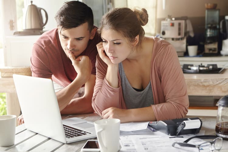 young couple looking at laptop and papers together - FMLA