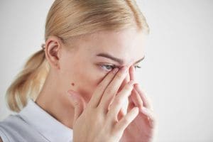 excessive alcohol consumption, alcohol eyes, effects of alcohol on the eyes, eye damage, alcohol eye floaters, alcoholic eyes, pretty blonde woman with her hands up to her eyes - excessive alcohol use and your eyes