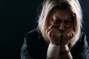 shadowed shot of extremely distraught woman with a gauze bandage wrapped around one wrist - PTSD