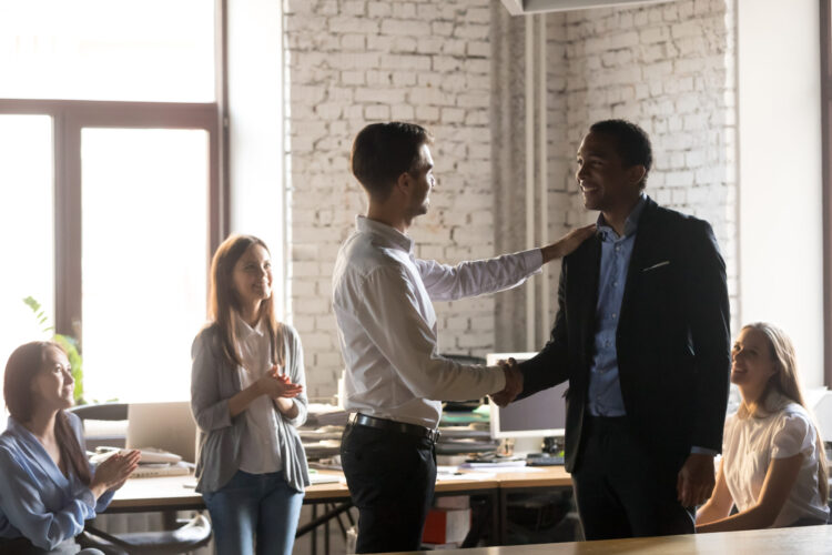 Boss thanking African American employee for good work, handshaking