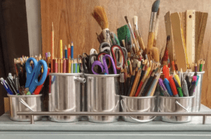 Art supplies, including paint brushes, colored pencils, rulers, and scissors.