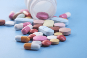 A bottle with many pills spilled out of it.