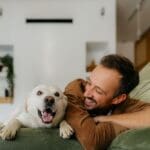 A man and his dog are comfortably lying together on a couch, enjoying a moment of relaxation.